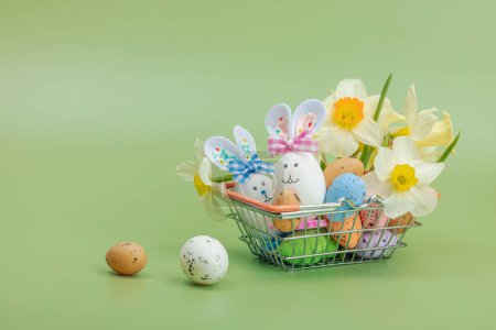 Easter sale concept. Shopping basket with festive symbols - rabbit, eggs, bird, and traditional decor. Pastel design, green background, copy space