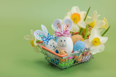 Easter sale concept. Shopping basket with festive symbols - rabbit, eggs, bird, and traditional decor. Pastel design, green background, close up