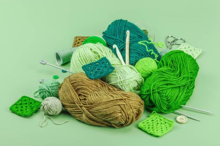 A set of knitting yarn and tools in spring colors. Handmade concept, creative art, crafting process. Hobby, relax, lifestyle, flat lay on pastel green background, close up