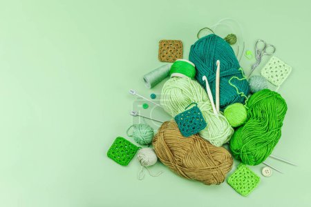 A set of knitting yarn and tools in spring colors. Handmade concept, creative art, crafting process. Hobby, relax, lifestyle, flat lay on pastel green background, top view