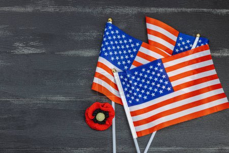 Memory Day concept. United States of America flags and handmade crochet poppy flower. Traditional symbols, flat lay, black wooden background, top view