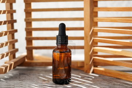 Foto de Botella de vidrio Mock-Up. botella de aceite cosmético con sombras de pared de madera, tratamiento corporal y spa. Productos de belleza natural. Suero ecológico - Imagen libre de derechos