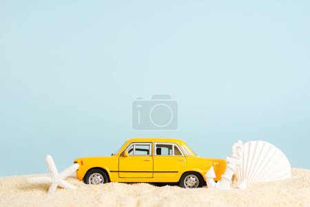Coche de taxi de juguete con conchas marinas en arena de playa, fondo azul. servicio de reserva de taxi. Viajar. Hora de verano, espacio para el texto