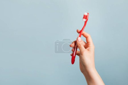 Téléchargez les photos : Femme tenant une brosse à dents rouge sur fond bleu, espace de copie - en image libre de droit