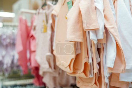 Téléchargez les photos : Vêtements de bébé suspendus aux cintres dans le centre commercial - en image libre de droit