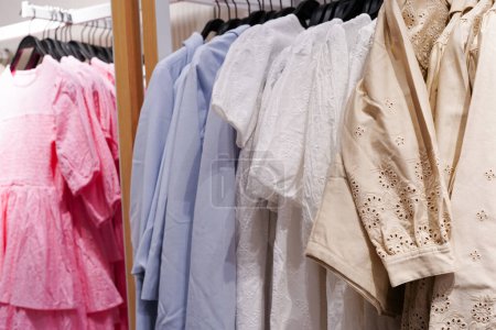 Téléchargez les photos : Robes de fille vêtements enfants accroché sur cintres dans la boutique - en image libre de droit