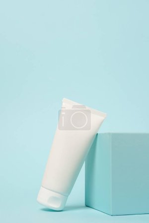 Photo for White cosmetic tube on the podium on blue background, copy space - Royalty Free Image