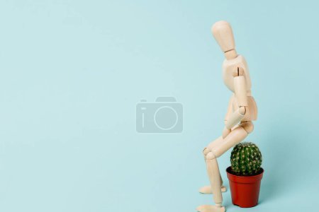 Hemorroides. hombre de madera sentado en un cactus. Estructuras vasculares en la parte inferior del recto y concepto de dolor agudo, fondo azul con espacio para copiar