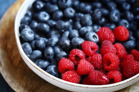 Fresh selected raspberries and blueberries in a bowl. Healthy snack. Berries for dessert. Close-up.