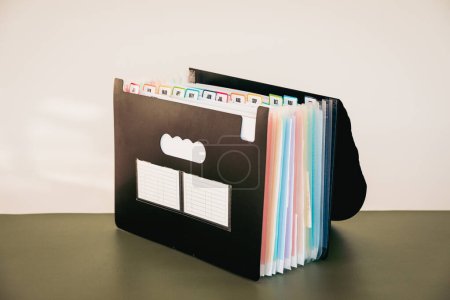 Photo for 12-Month Accordion File Organizer, Monthly Document Filing System with Color-Coded Tabs for Home Office and a Stack of Receipts for Tax Filing, January to December Tabs - Royalty Free Image