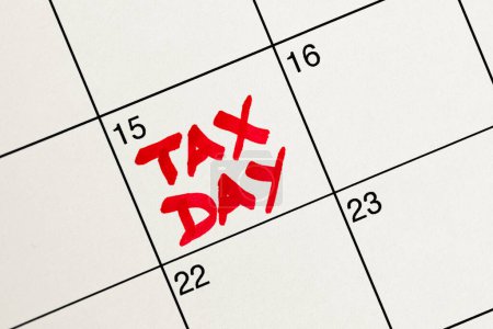 Photo for April 15th highlighted in red as Tax Day on a white calendar for income tax filing reminder, flat lay, top-down view, handwriting with red marker - Royalty Free Image