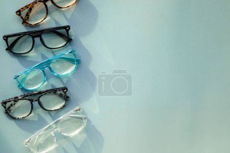 Téléchargez les photos : Un assortiment de lunettes de lecture bloquant la lumière bleue sur fond solide bleu clair avec espace de copie - en image libre de droit