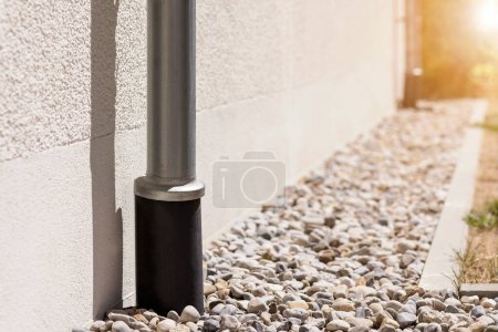 Photo for Storm Drainage Drain Downspout Pipe  Installing into French drain with  Drainage Stones Outside Building. Stormwater pipe on facade with Drain Gravel - Royalty Free Image