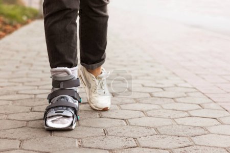 Photo for Orthopedic walking Boots. Woman with Ankle Injury, fracture or ankle sprain. Busted Ankle Brace broken leg, short leg cast, splint for treatment of injured woman leg - Royalty Free Image
