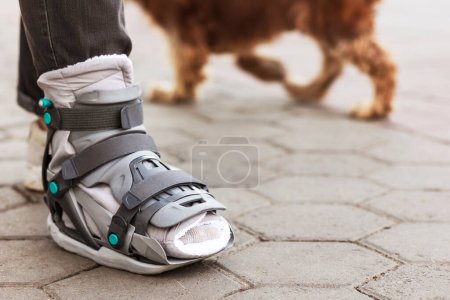Photo for Ankle Splint Boots or Leg Orthosis Bandage Shoes allows to walk the Dog Outdoor. - Royalty Free Image