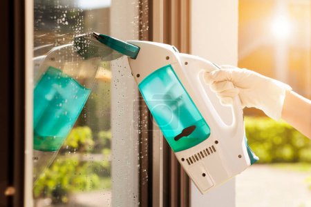 Photo for Cleaning Window Glass with Electrical Device. Close up of Woman's Gloved hand Washing Window with Electro Machine - Royalty Free Image