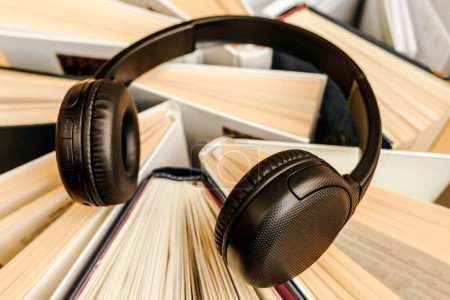 Téléchargez les photos : Audio Book concept with large heap of Books and Headphones. Online Studying, Learning or Self Study. Book Day. - en image libre de droit