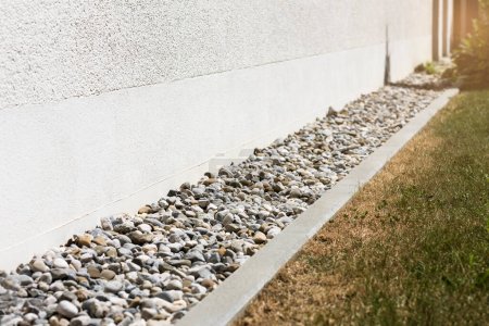 French drain or Drain Rainwater with Drainage Stones or Gravel along House Wall. Drainage System Floor of Modern Exterior Design Building.