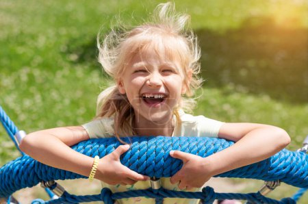 Happy Summer Holiday. Funny Kid Swinging Having fun on Nature Background. Smiling Child Emotion Portrait on Swing.