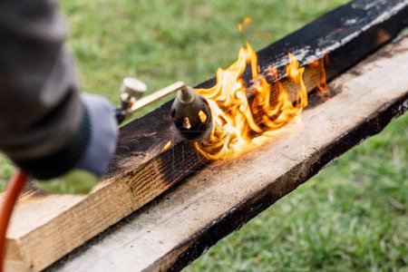 Foto de Burning Charring Wood Board with Fire Flame es una forma de proteger la madera. Preservar madera moderna para usar al aire libre. - Imagen libre de derechos