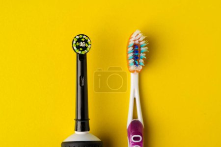 Photo for Electric and manual toothbrushes on a yellow background, close-up. - Royalty Free Image