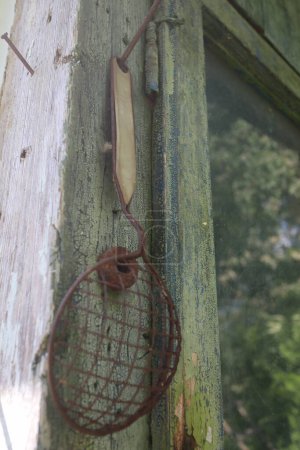 very old rusty handle colander strainer hanging on the wall