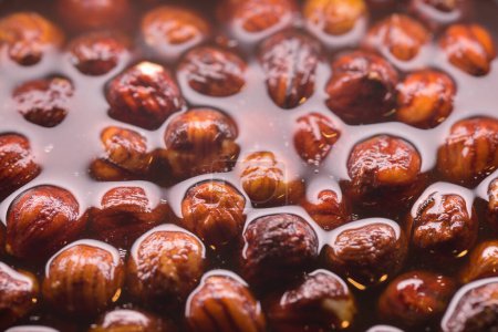 Photo for Dipping of natural hazelnuts in pure rum for softening before making cookie  dough - Royalty Free Image