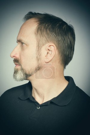 Téléchargez les photos : Portrait d'homme vieillissant essayant des expressions en studio en chemise noire - en image libre de droit