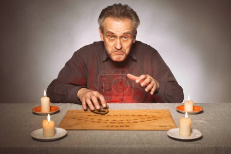 Photo for Older spiritist communicating with ghosts through ouija - Royalty Free Image