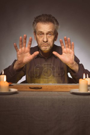 Foto de Espírita mayor comunicándose con fantasmas a través de ouija - Imagen libre de derechos