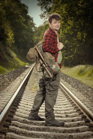 Photo for Adventurer with retro haversack wandering nature on railroad way - Royalty Free Image