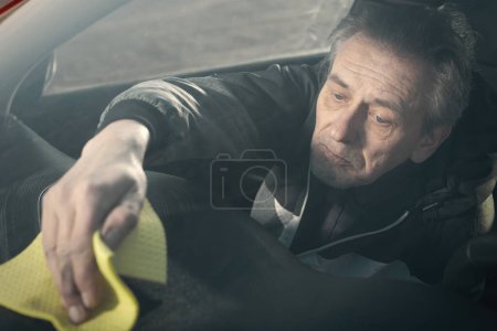 Téléchargez les photos : Homme plus âgé prendre soin annd nettoyage intérieur de la voiture sur la nature parking - en image libre de droit
