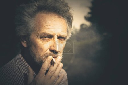 Photo for Aged man smoking cigarettes in city park lately on day time - Royalty Free Image