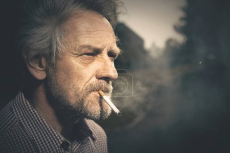 Foto de Hombre anciano fumando cigarrillos en el parque de la ciudad últimamente durante el día - Imagen libre de derechos