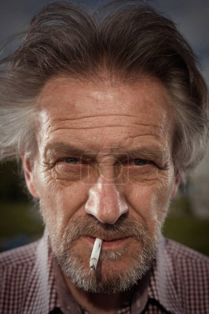 Photo for Aged man smoking cigarettes in city park lately on day time - Royalty Free Image