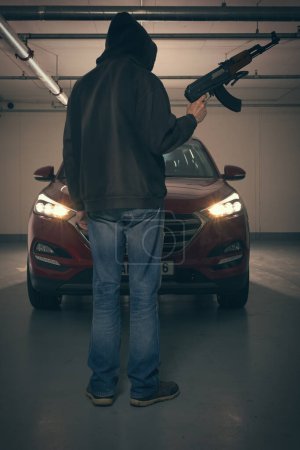 Téléchargez les photos : Homme en chemise à capuche noire armé d'un pistolet automatique à la recherche d'un danger - en image libre de droit