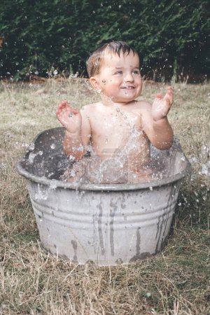 Téléchargez les photos : Petit garçon refroidissant dans une petite baignoire en tôle rétro - en image libre de droit