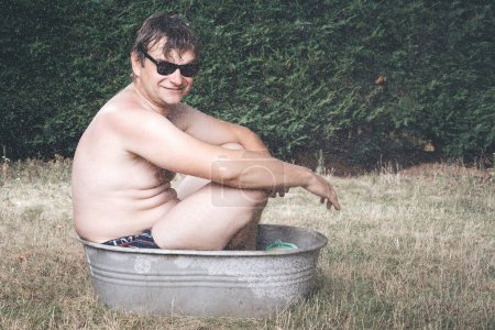 Téléchargez les photos : Homme de refroidissement dans la baignoire en métal rétro pour les enfants en été chaude de jour - en image libre de droit