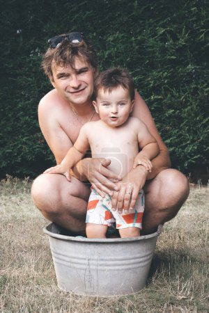 Foto de Padre e hijo enfriándose en una pequeña bañera de chapa retro - Imagen libre de derechos