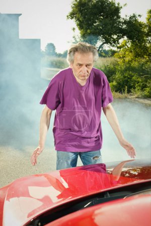 Photo for Pensioner checking state of his car with smoking engine - Royalty Free Image