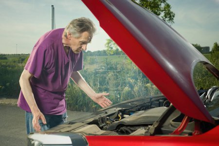 Photo for Pensioner checking state of his car with smoking engine - Royalty Free Image