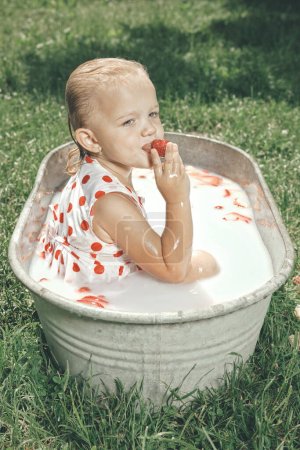 Foto de Niña disfrutando de baño en bañera de chapa retro en el parque - Imagen libre de derechos