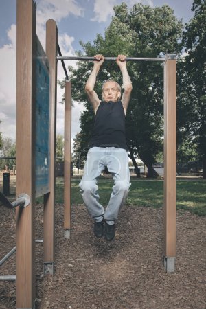 Foto de Hombre feo de mal estado tratando de hacer ejercicio en el gimnasio al aire libre - Imagen libre de derechos