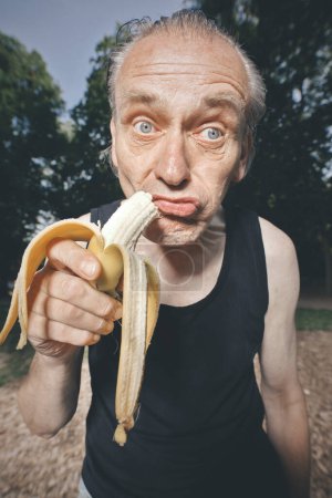 Téléchargez les photos : Laide homme de mauvaise condition manger de la banane fraîche après l'entraînement - en image libre de droit