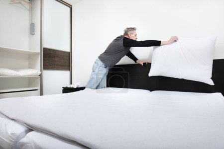 Foto de Hombre mayor trabajando en el dormitorio en hacer la cama - Imagen libre de derechos