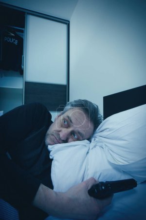 Photo for Police officer waking up in his bedroom afraid of intruder - Royalty Free Image