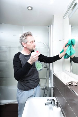 Photo for Older man cleaning bathroom space in apartment - Royalty Free Image