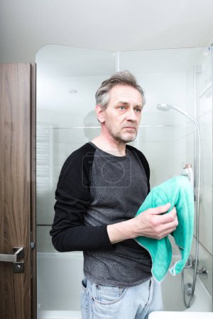 Téléchargez les photos : Homme plus âgé nettoyage salle de bains dans l'appartement - en image libre de droit