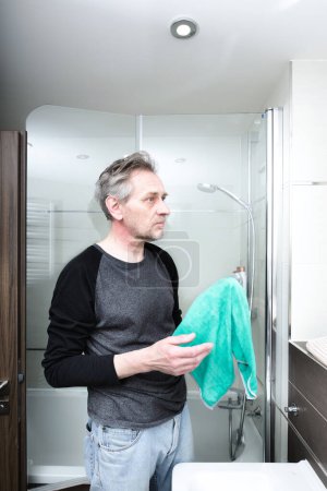 Téléchargez les photos : Homme plus âgé nettoyage salle de bains dans l'appartement - en image libre de droit