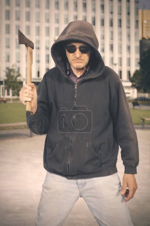 Photo for Aggressive older man with axe under the influence of drugs in park - Royalty Free Image